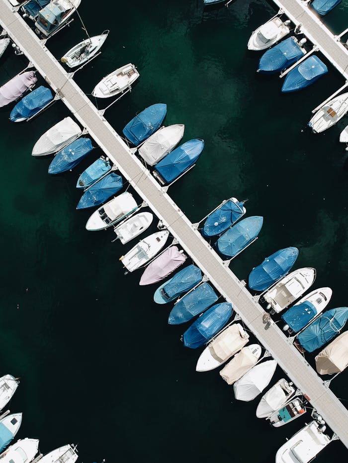 An aerial shot capturing luxury yachts docked at a marina with clear blue waters.