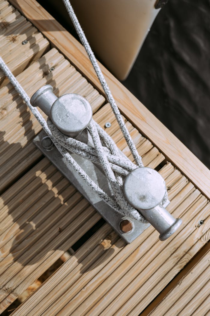 Detailed view of a moored cleat with ropes at a marina dock.